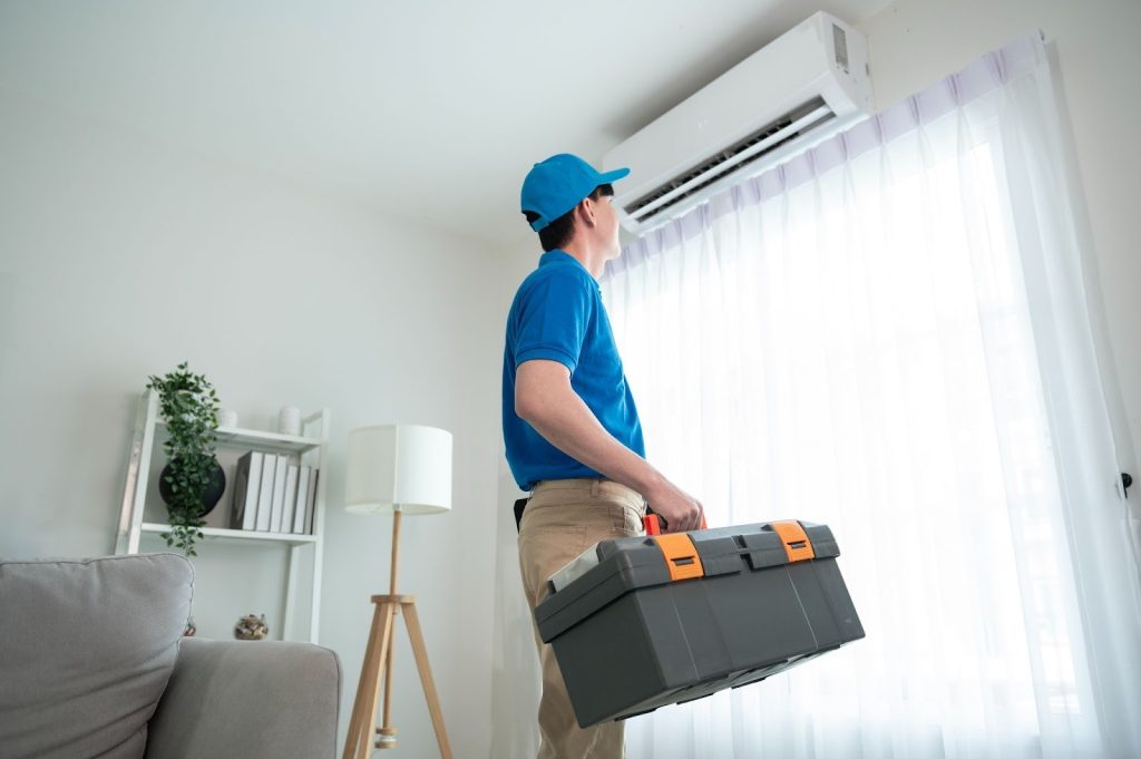 HVAC service technician inspecting a residential air conditioner unit indoors